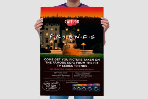 A person holding a designed copy of a CaféPod Friends promotional poster