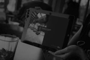A black and white image of a woman holding a tablet showing the JLL Pinnacle Tower investment memorandum design