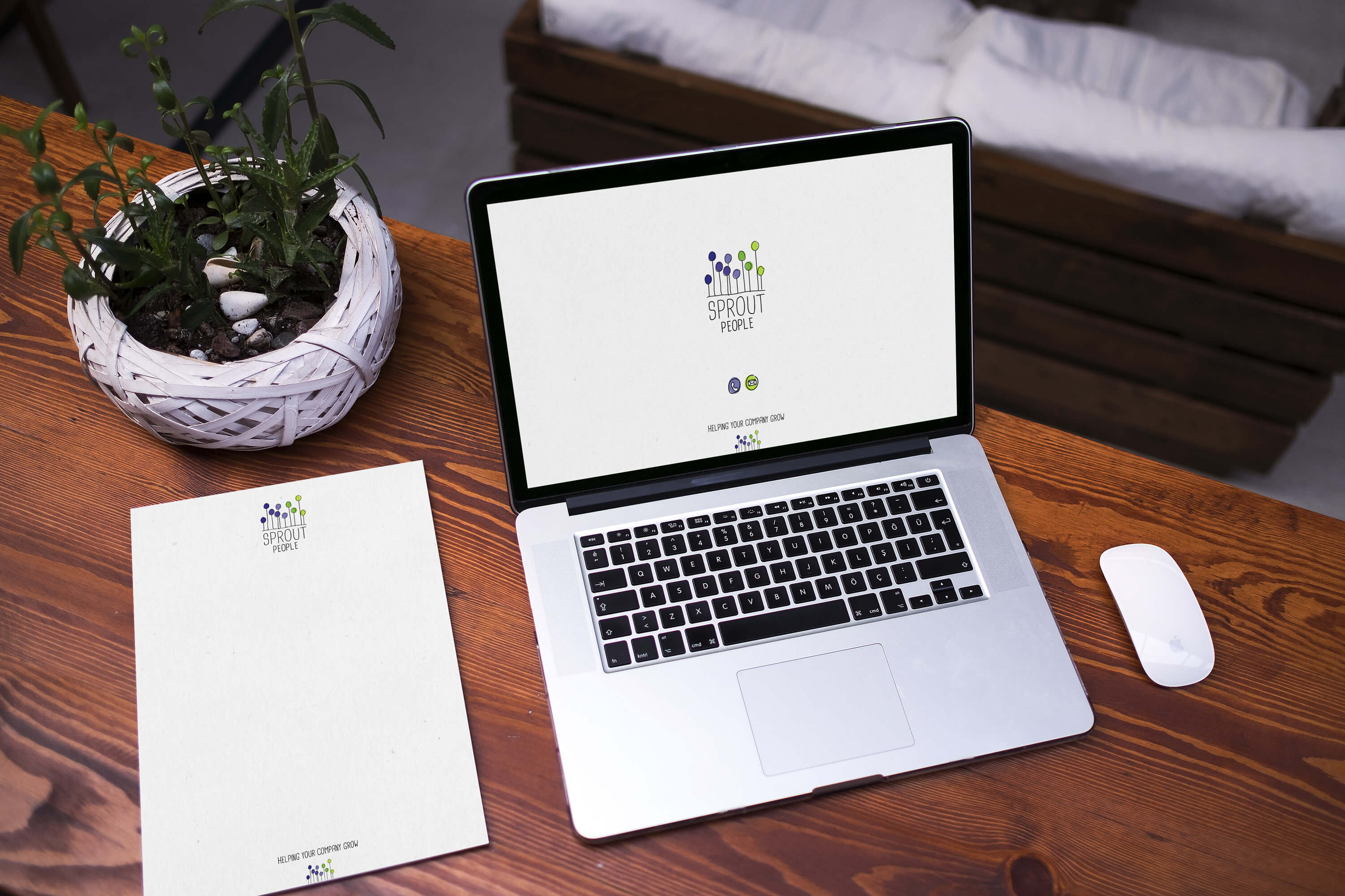 A laptop and letterhead on a desk showing the Sprout People brand identity